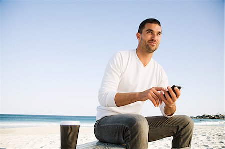 Man using mobile phone on a beach Stock Photo - Premium Royalty-Free, Code: 614-05557162