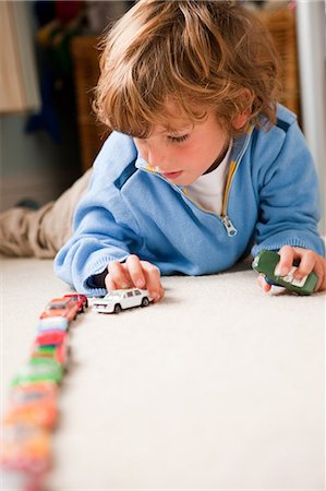 Young boy lining up toy cars in his bedroom Stock Photo - Premium Royalty-Free, Code: 614-05650616
