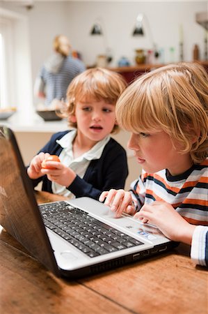 family computer kitchen - Young boy using laptop with his younger brother looking across at the monitor Stock Photo - Premium Royalty-Free, Code: 614-05650651