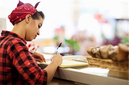 service counter - Young woman writing on counter of bakery Stock Photo - Premium Royalty-Free, Code: 614-05662177