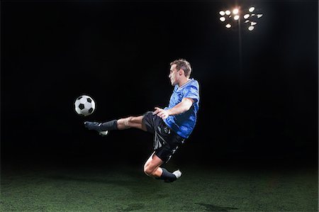 soccer player - Young soccer player leaping into air to kick ball Stock Photo - Premium Royalty-Free, Code: 614-05662287