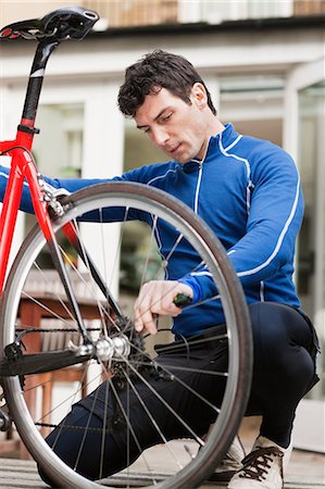 Mid adult man adjusting bicycle wheel Stock Photo - Premium Royalty-Free, Code: 614-05662316