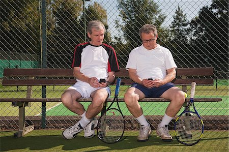 Senior and mature men texting on tennis court Stock Photo - Premium Royalty-Free, Code: 614-05792220