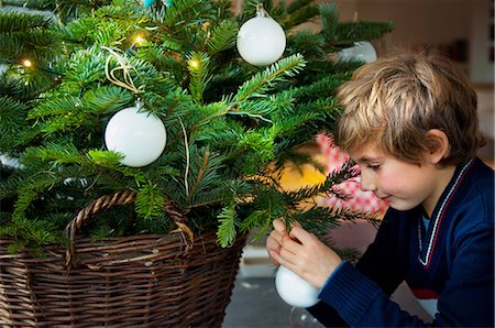 Boy decorating Christmas tree with baubles at home Stock Photo - Premium Royalty-Free, Code: 614-05792380
