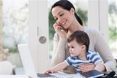 parents with baby boy in pictures - Mother on cellphone and baby looking at laptop Stock Photo - Premium Royalty-Free, Code: 614-05955635