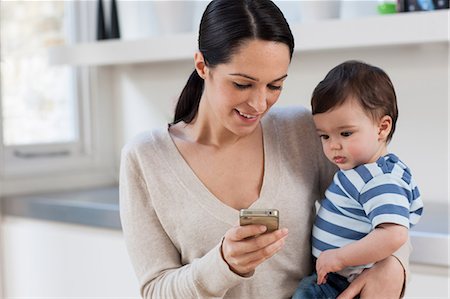 picture of a baby boy smiling - Mother and baby son looking at smartphone Stock Photo - Premium Royalty-Free, Code: 614-05955649