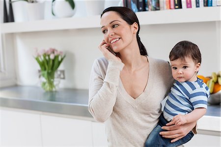 parents with baby boy in pictures - Mother on cellphone, holding baby son Stock Photo - Premium Royalty-Free, Code: 614-05955643