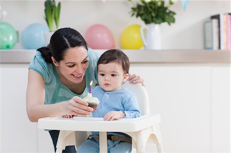 picture of a baby boy smiling - Mother giving birthday cupcake to baby son in high chair Stock Photo - Premium Royalty-Free, Code: 614-05955677