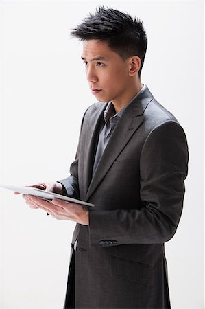 side view boys pic - Young Asian businessman holding digital tablet, studio shot Stock Photo - Premium Royalty-Free, Code: 614-06002456