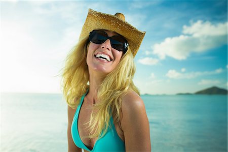 sunglasses - Happy woman in sunglasses and cowboy hat by the ocean Stock Photo - Premium Royalty-Free, Code: 614-06002608
