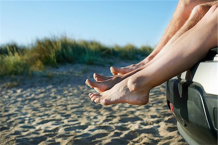 Mid adult couple sitting barefoot on car on beach Stock Photo - Premium Royalty-Free, Code: 614-06044322