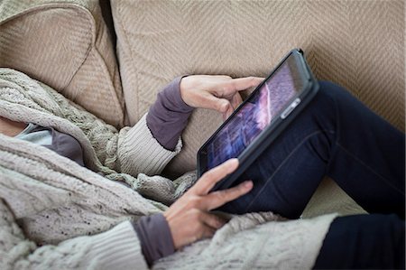 Senior woman using digital laptop on sofa, mid section Stock Photo - Premium Royalty-Free, Code: 614-06044618