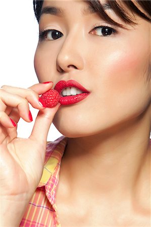 raspberry - Young woman eating raspberry, portrait Stock Photo - Premium Royalty-Free, Code: 614-06044660