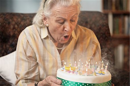 Senior woman blowing out birthday candles Stock Photo - Premium Royalty-Free, Code: 614-06043826