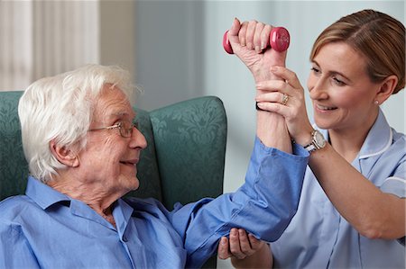 Carer assisting senior man with hand weights Stock Photo - Premium Royalty-Free, Code: 614-06043855