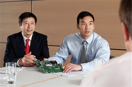 Businessmen discussing circuit board in meeting Stock Photo - Premium Royalty-Free, Code: 614-06116527