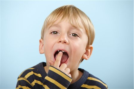 Boy pointing to gap in teeth Stock Photo - Premium Royalty-Free, Code: 614-06168899