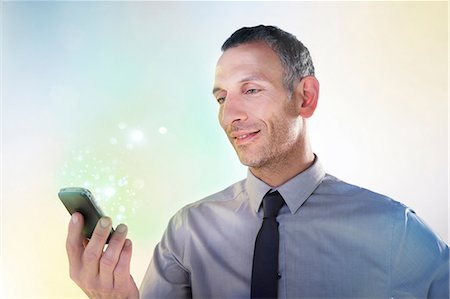 simsearch:614-05399875,k - Businessman holding cellphone with lights Stock Photo - Premium Royalty-Free, Code: 614-06169332