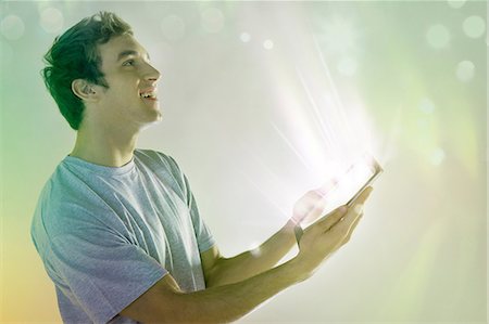 futuro - Young man looking at light coming digital tablet Fotografie stock - Premium Royalty-Free, Codice: 614-06169353