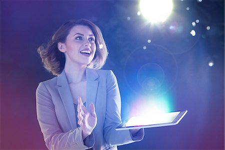 Young woman looking at lights coming from digital tablet Stock Photo - Premium Royalty-Free, Code: 614-06169443
