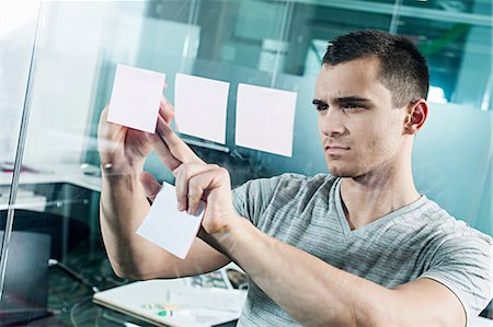 Man sticking adhesive note to window Stock Photo - Premium Royalty-Free, Code: 614-06311925