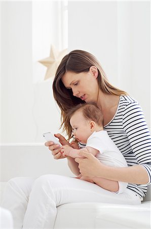 Mother holding baby and using cellphone Stock Photo - Premium Royalty-Free, Code: 614-06312019