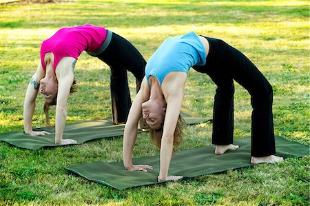 Two women bending over backwards on yoga mats outdoors Stock Photo - Premium Royalty-Free, Code: 614-06336336