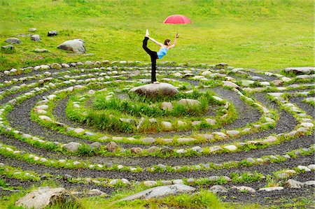 Woman holding an umbrella whilst in yoga pose in centre of stone maze Foto de stock - Sin royalties Premium, Código: 614-06402797