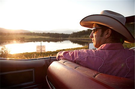 Man in cowboy hat, looking at lake from his car Stock Photo - Premium Royalty-Free, Code: 614-06402860