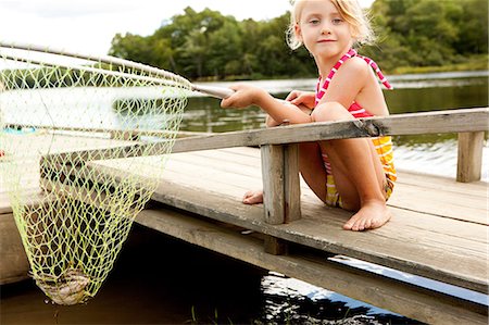 Girl on jetty with frog in fishing net Stock Photo - Premium Royalty-Free, Code: 614-06402889