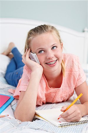 Teenage girl on cellphone with notepad Stock Photo - Premium Royalty-Free, Code: 614-06403031