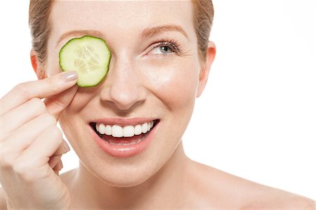Woman holding a cucumber slice to her eye Stock Photo - Premium Royalty-Free, Code: 614-06442372