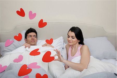 Couple in bed with heart shapes on bedclothes Stock Photo - Premium Royalty-Free, Code: 614-06442395