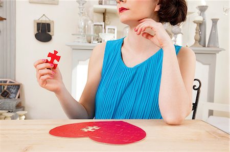 Woman doing heart shaped jigsaw puzzle holding piece Stock Photo - Premium Royalty-Free, Code: 614-06442405