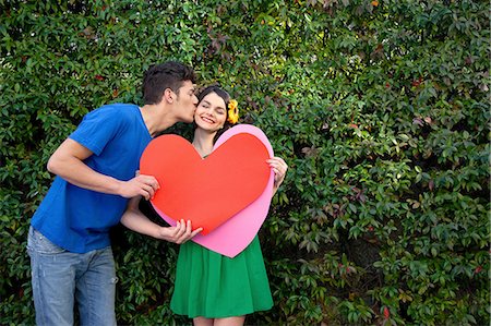 Couple holding heart shape, man kissing woman Stock Photo - Premium Royalty-Free, Code: 614-06442432