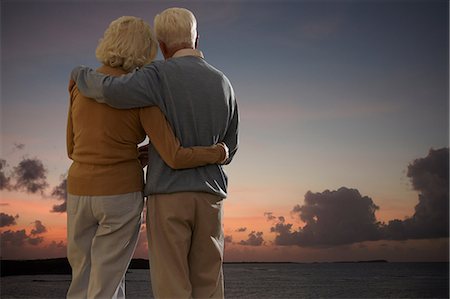 supportive hug - Senior couple looking out to sea together at sunset Stock Photo - Premium Royalty-Free, Code: 614-06442458