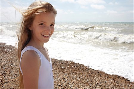 Girl on shingle beach by the sea, smiling at camera Stock Photo - Premium Royalty-Free, Code: 614-06442488