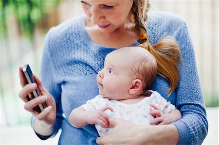 Mother holding newborn daughter and cell phone Stock Photo - Premium Royalty-Free, Code: 614-06442533