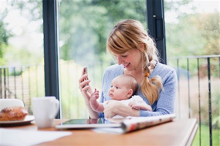 Mother with cell phone and newborn daughter Stock Photo - Premium Royalty-Free, Code: 614-06442561