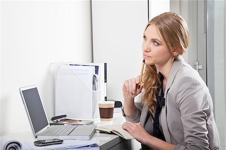 Young woman at her desk, thinking Stock Photo - Premium Royalty-Free, Code: 614-06442762