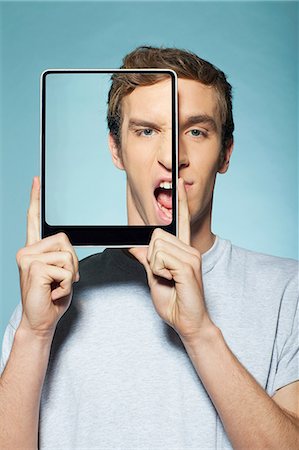 Man covering half his face with digital tablet Foto de stock - Sin royalties Premium, Código: 614-06442913