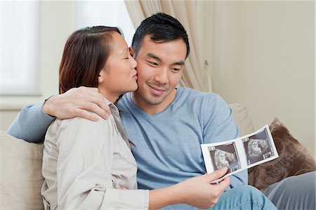 pregnant women kissing - Couple examining sonogram on sofa Stock Photo - Premium Royalty-Free, Code: 614-06536928