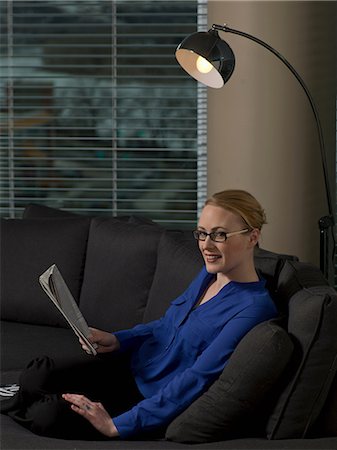 Businesswoman reading newspaper on sofa Stock Photo - Premium Royalty-Free, Code: 614-06624200