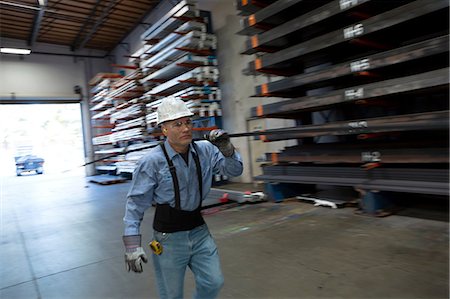 Worker carrying pipes in metal plant Stock Photo - Premium Royalty-Free, Code: 614-06624483
