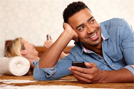Smiling man using cell phone indoors Stock Photo - Premium Royalty-Free, Code: 614-06625131