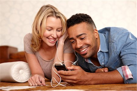 Couple listening to headphones on bed Stock Photo - Premium Royalty-Free, Code: 614-06625133