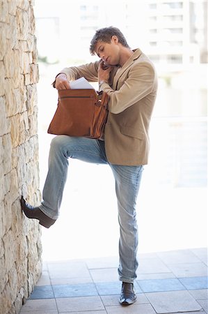 Businessman rooting through briefcase Stock Photo - Premium Royalty-Free, Code: 614-06623851