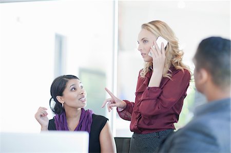 Businesswoman taking call by colleague Stock Photo - Premium Royalty-Free, Code: 614-06718454