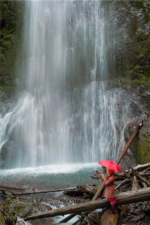 Woman with umbrella admiring waterfall Stock Photo - Premium Royalty-Free, Code: 614-06719889