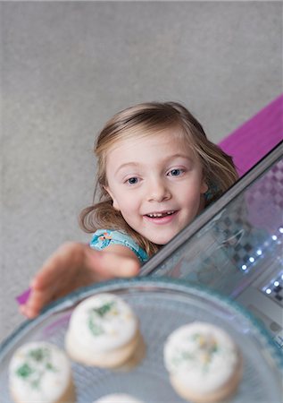 reaching - Girl reaching for cupcakes in bakery Stock Photo - Premium Royalty-Free, Code: 614-06719943